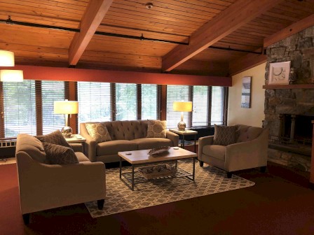 Cozy living room with sofas, a fireplace, wood ceiling, and lamps.